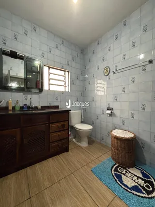 Foto de um banheiro com revestimento de azulejos e móveis de madeira escura.