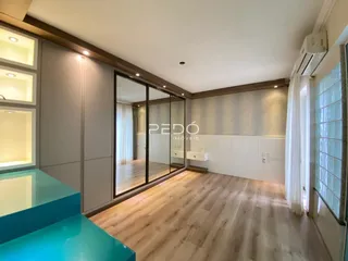 Interior de uma sala de estar com piso de madeira e portas de vidro.