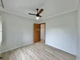 Interior de uma sala com piso de madeira clara e paredes brancas.