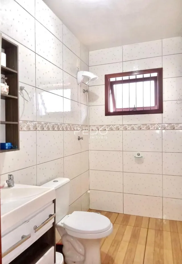 Banheiro com revestimento cerâmico e piso de madeira.