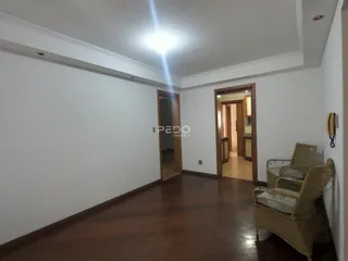 Interior de uma sala com piso de madeira e portas abertas.