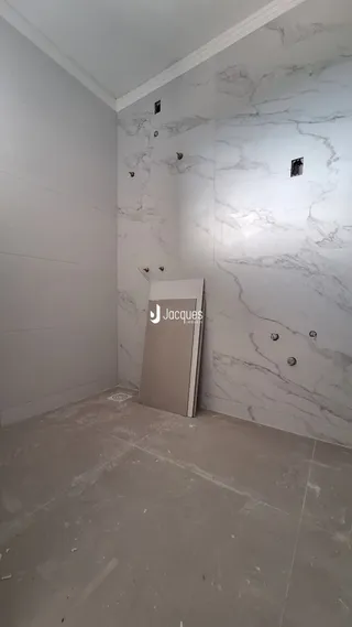 Vista interna de um corredor com paredes brancas e piso de concreto.