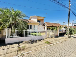 Vista da fachada de uma residência em Lajeado, Brasil, com cerca branca e portão.