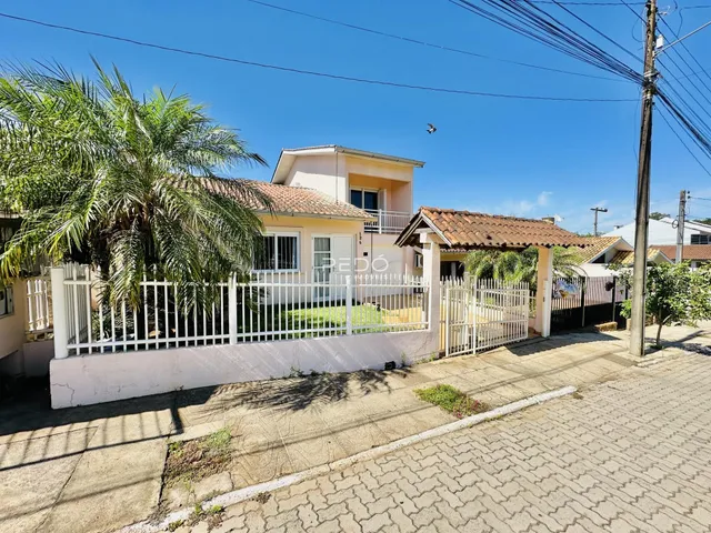 Vista da fachada de uma residência em Lajeado, Brasil, com cerca branca e portão.