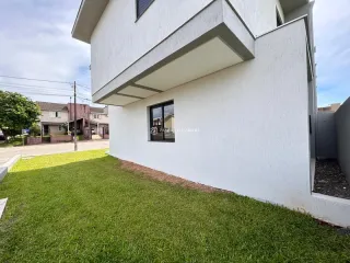 Fachada externa de uma casa branca com jardim em Lajeado, Brasil.