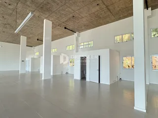 Interior de um espaço amplo com teto de concreto aparente e colunas brancas.