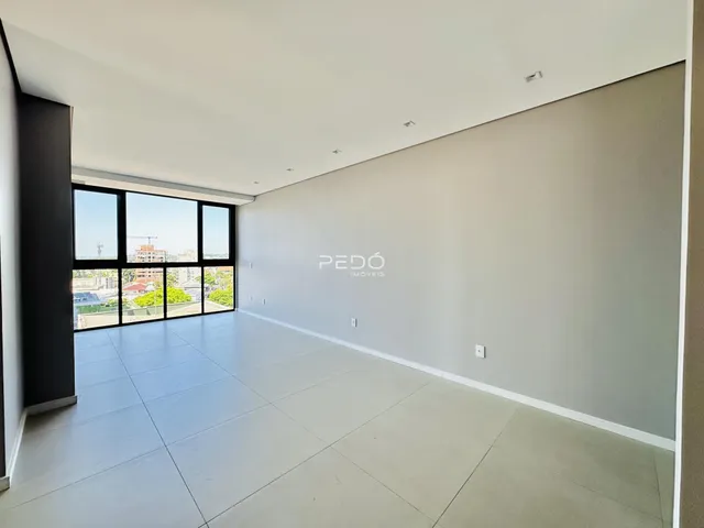Ambiente interno amplo com piso claro e grandes janelas.