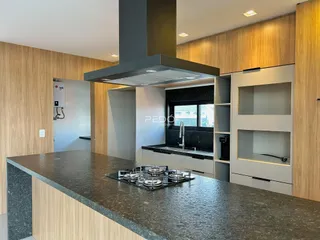 Cozinha moderna com armários de madeira e bancadas escuras.