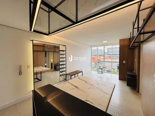 Ambiente moderno de sala de estar com pé direito alto e grandes janelas.
