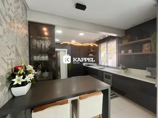 Cozinha moderna com ilha escura e bancadas claras em ambiente bem iluminado.