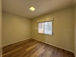 Ambiente interno de uma sala com piso de madeira e janela.