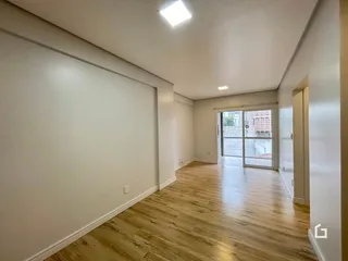 Interior de um ambiente com piso de madeira clara e paredes brancas.