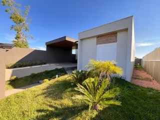 Vista externa de uma casa com gramado e vegetação ao ar livre.