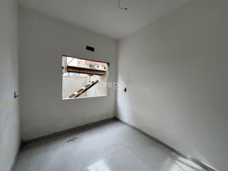 Ambiente interno de uma sala com paredes brancas e piso claro.