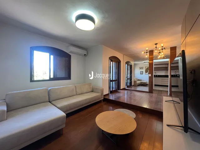 Sala de estar com sofá e piso de madeira em um imóvel no Brasil.