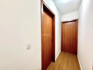 Hall de entrada com portas de madeira e piso de madeira clara.