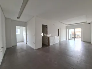 Interior de uma sala ampla com paredes brancas e piso de concreto.