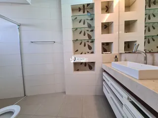 Banheiro moderno com revestimento branco e bancada de mármore.