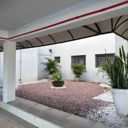 Área externa com piso de cascalho e vegetação.
