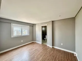 Sala de estar com piso de madeira e janela com vista para a cidade.