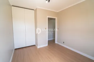 Interior de um ambiente com paredes brancas e piso de madeira clara.