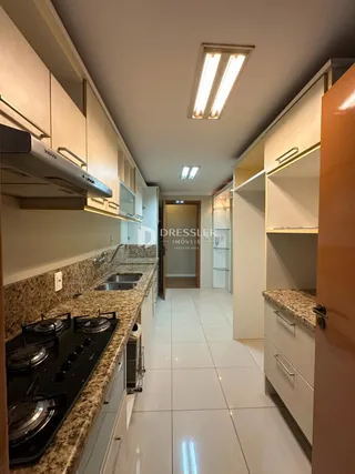 Vista da cozinha com armários e bancadas em um imóvel no Brasil.