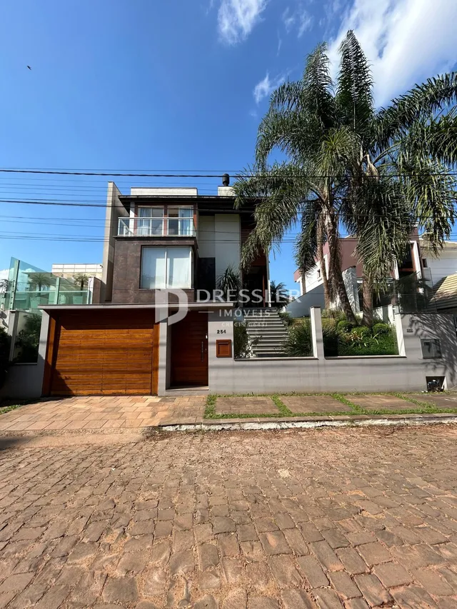 Fachada de uma residência em Lajeado, Brasil, com jardim e portão de madeira.