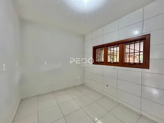 Ambiente interno de uma sala com piso de cerâmica e parede branca.