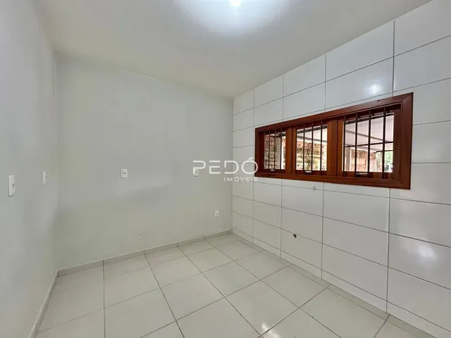Ambiente interno de uma sala com piso de cerâmica e parede branca.