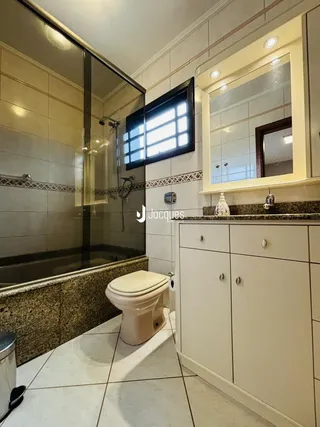 Banheiro com box de vidro e revestimento cerâmico.