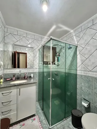 Foto de um banheiro com box de vidro e revestimento de azulejos