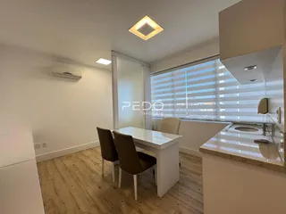 Ambiente interno de uma sala com mesa de jantar e piso de madeira.