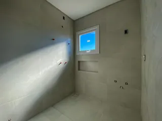 Interior de um cômodo com paredes cinzas e uma janela com vista para o céu azul.