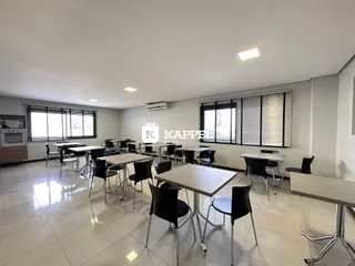 Foto de uma sala de jantar com mesas e cadeiras em um ambiente bem iluminado.