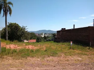 Vista externa da propriedade com muro de tijolos e vegetação