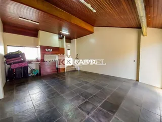 Ambiente interno com piso de ladrilho e forro de madeira em uma área comum.