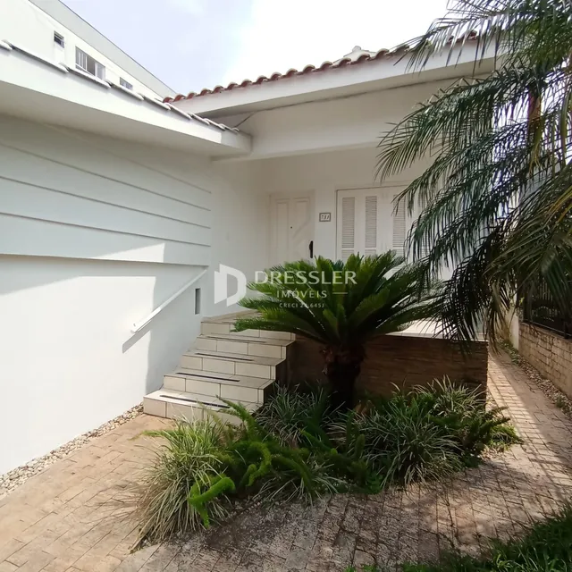 Fachada de uma casa branca em Lajeado, Brasil, com jardim tropical na frente.