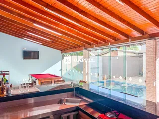 Ambiente interno com forro de madeira e vista para a área externa com piscina.
