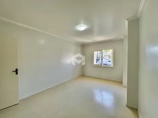 Ambiente interno de uma sala ampla com paredes brancas e piso claro.