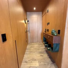 Corredor interno com revestimento de madeira nas paredes e piso de madeira clara.