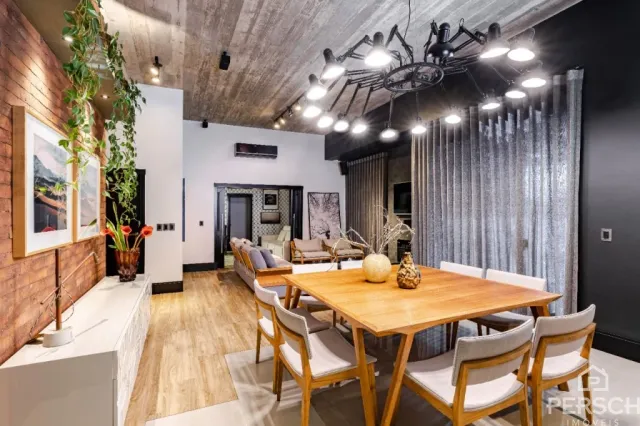 Uma sala de estar com mesa de madeira e iluminação industrial.