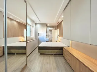 Quarto moderno com cabeceira e armários em madeira.
