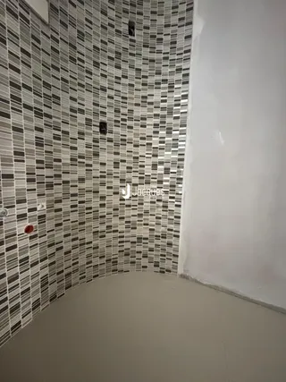 Parede com revestimento cerâmico em tons de cinza e bege em um ambiente interno.