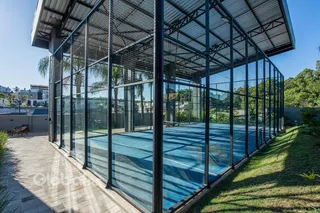 Foto de uma área externa com piscina cercada por uma estrutura de vidro.