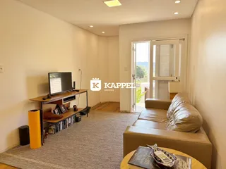 Uma sala de estar com sofá e televisão é apresentada no imóvel.
