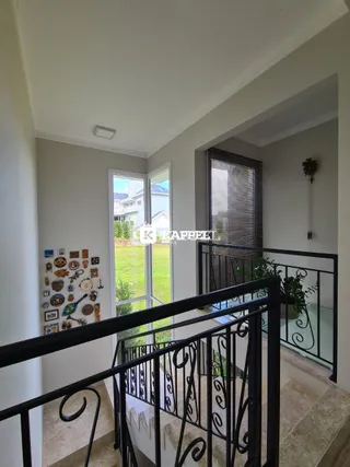 Vista de um corredor com escadaria de metal preto e janela para o exterior.