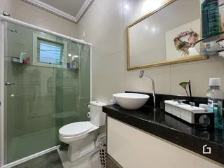 Banheiro com box de vidro e bancada escura.