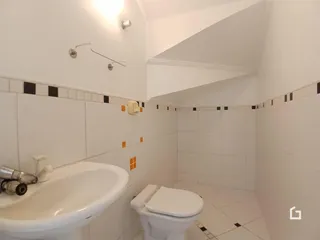 Banheiro com revestimento cerâmico nas paredes e piso branco.