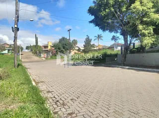 Vista externa de uma propriedade com paisagismo e área pavimentada.