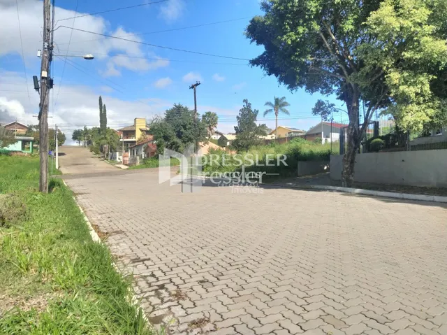 Vista externa de uma propriedade com paisagismo e área pavimentada.